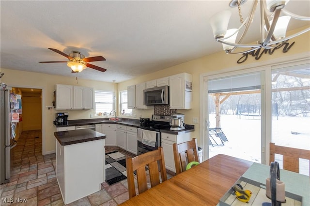 kitchen featuring white cabinetry, a center island, sink, ceiling fan with notable chandelier, and appliances with stainless steel finishes