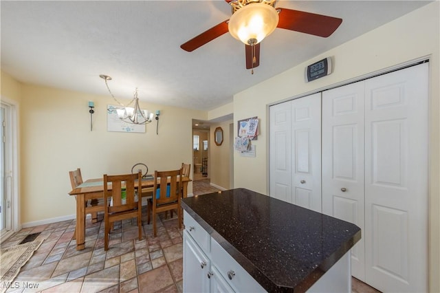 kitchen with ceiling fan with notable chandelier, a center island, and white cabinetry