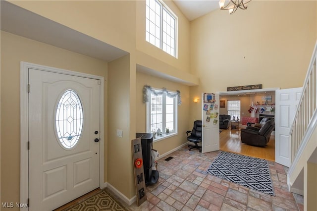 entrance foyer with a healthy amount of sunlight, light wood-type flooring, a high ceiling, and a chandelier