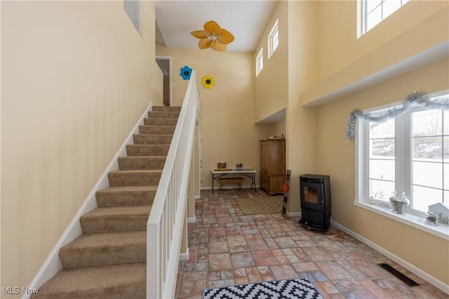 stairway featuring a wood stove and a high ceiling