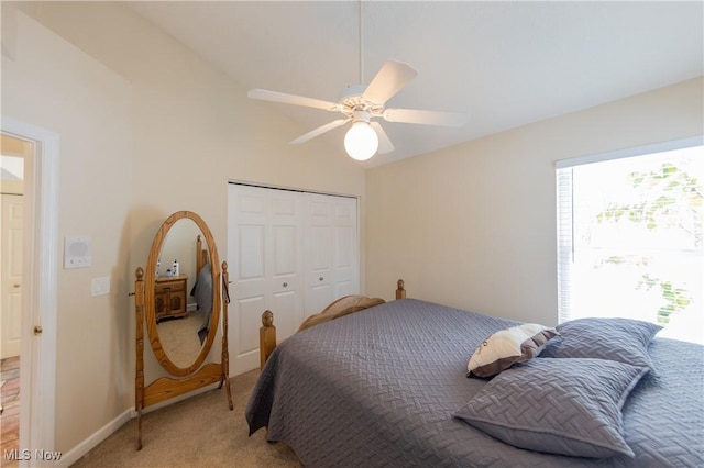 bedroom with ceiling fan, a closet, light colored carpet, and lofted ceiling