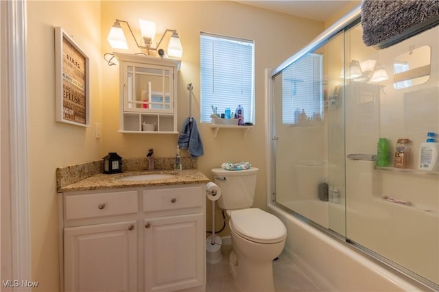 full bathroom featuring vanity, bath / shower combo with glass door, tile patterned flooring, toilet, and a healthy amount of sunlight