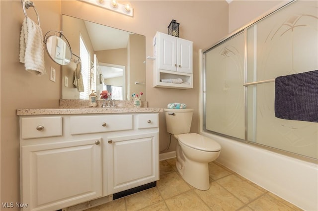 full bathroom featuring tile patterned floors, vanity, toilet, and bath / shower combo with glass door