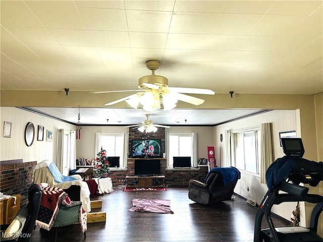 living room featuring crown molding, plenty of natural light, wood-type flooring, and brick wall