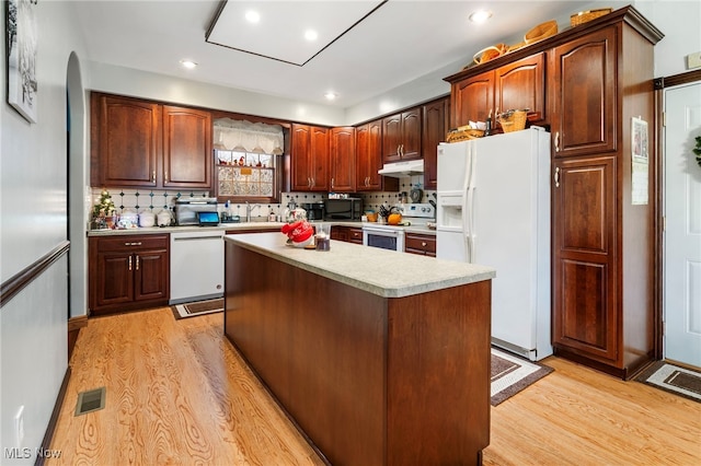 kitchen featuring light hardwood / wood-style floors, a kitchen island, white appliances, and backsplash