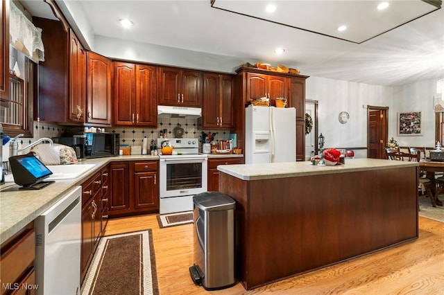 kitchen with a center island, white appliances, backsplash, sink, and light hardwood / wood-style floors