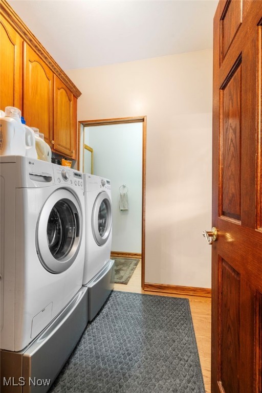 laundry area featuring cabinets, separate washer and dryer, and light hardwood / wood-style floors