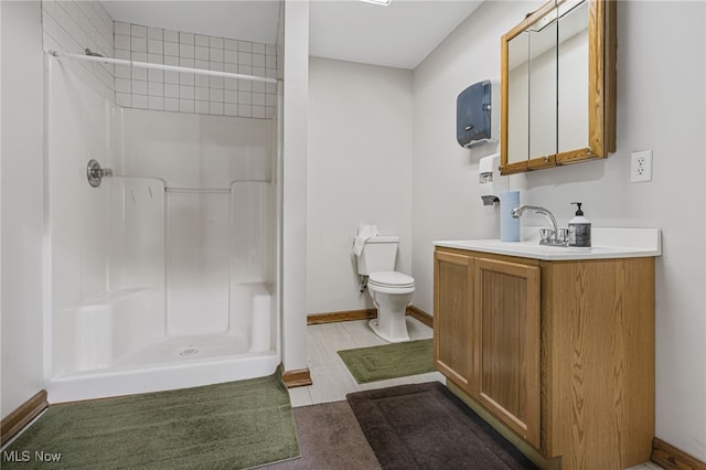 bathroom featuring a tile shower, vanity, and toilet