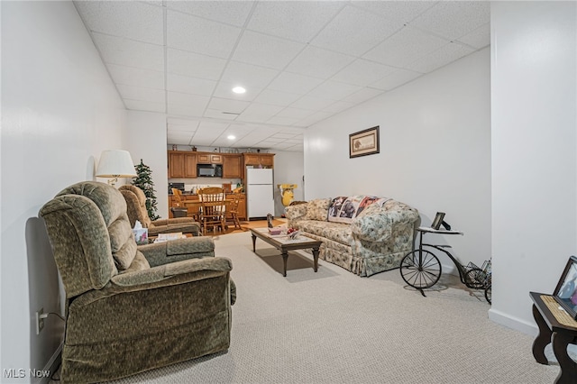 carpeted living room featuring a drop ceiling