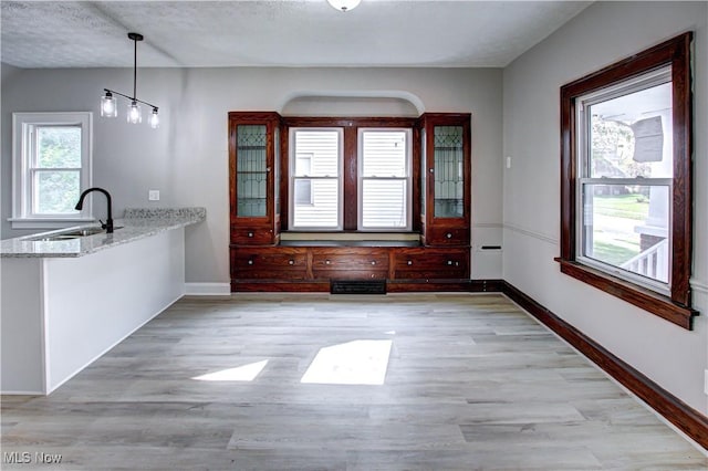 unfurnished dining area with a textured ceiling, light hardwood / wood-style floors, plenty of natural light, and sink