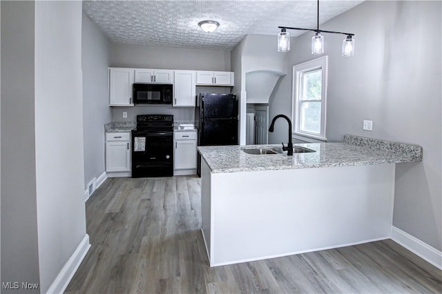 kitchen with kitchen peninsula, sink, white cabinetry, and black appliances