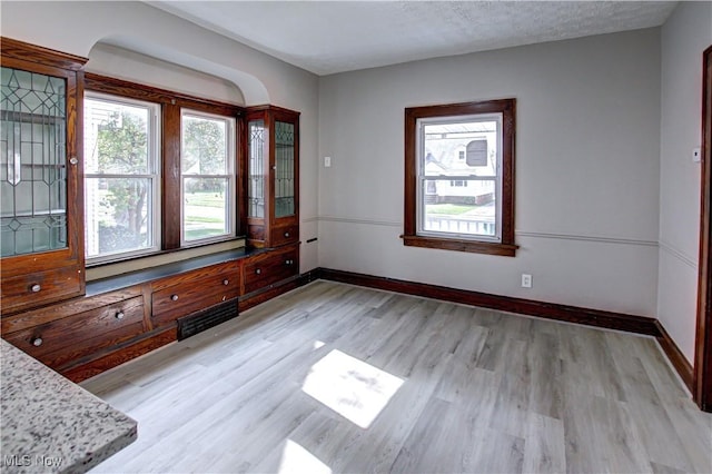 spare room featuring a textured ceiling and light hardwood / wood-style flooring