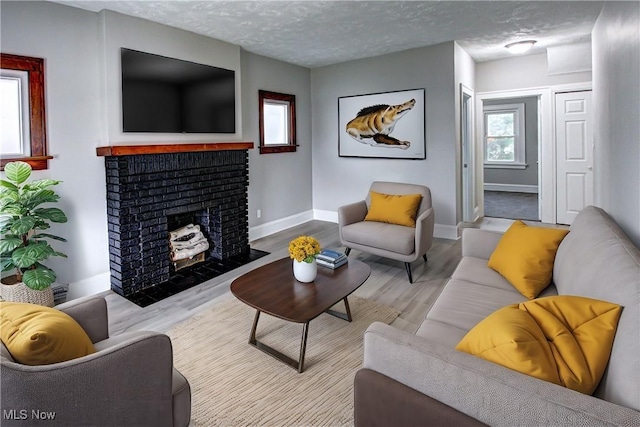 living room featuring a fireplace, light hardwood / wood-style floors, and a textured ceiling