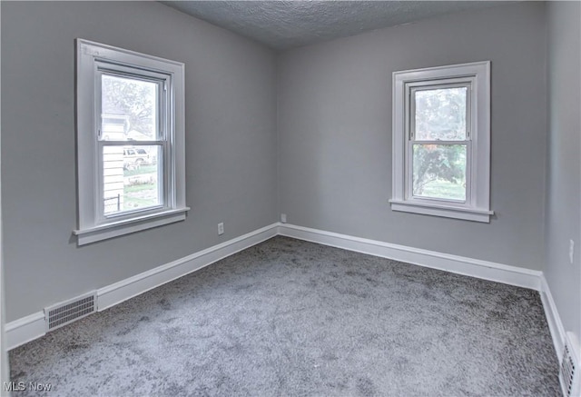 carpeted empty room with a textured ceiling