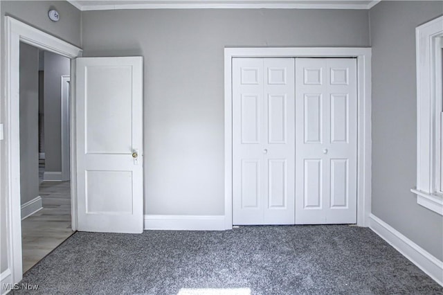 unfurnished bedroom with dark colored carpet and a closet