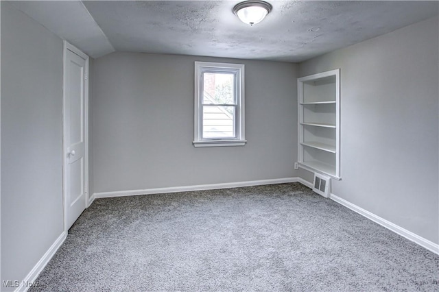 spare room featuring carpet flooring, a textured ceiling, and vaulted ceiling