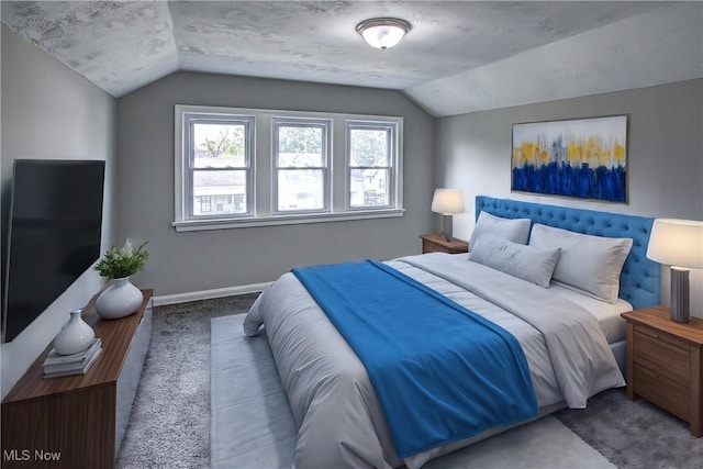 bedroom featuring carpet flooring, a textured ceiling, and lofted ceiling