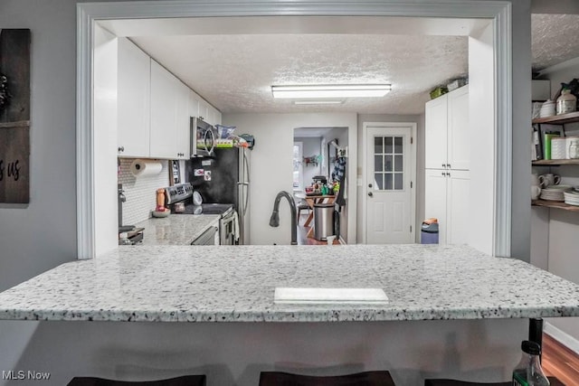 kitchen with white cabinets, wood-type flooring, a textured ceiling, and appliances with stainless steel finishes