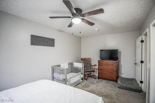 carpeted bedroom with ceiling fan and a textured ceiling