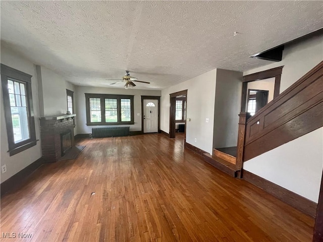 unfurnished living room featuring ceiling fan, radiator heating unit, dark wood-type flooring, and a textured ceiling