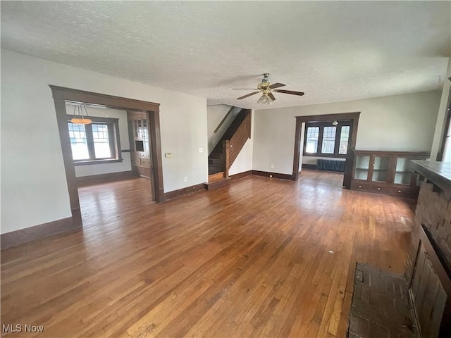 unfurnished living room featuring radiator heating unit, dark wood-type flooring, and plenty of natural light