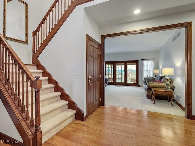 stairs with hardwood / wood-style floors and french doors