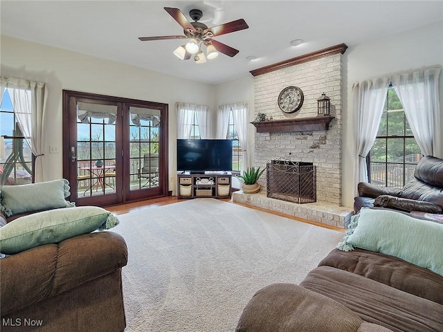 living room with ceiling fan, light hardwood / wood-style flooring, a wealth of natural light, and a brick fireplace