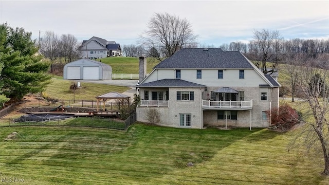 rear view of house featuring a lawn, a gazebo, an outdoor structure, a garage, and a deck