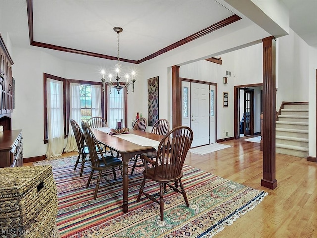 dining area with ornate columns, light hardwood / wood-style flooring, ornamental molding, and a notable chandelier