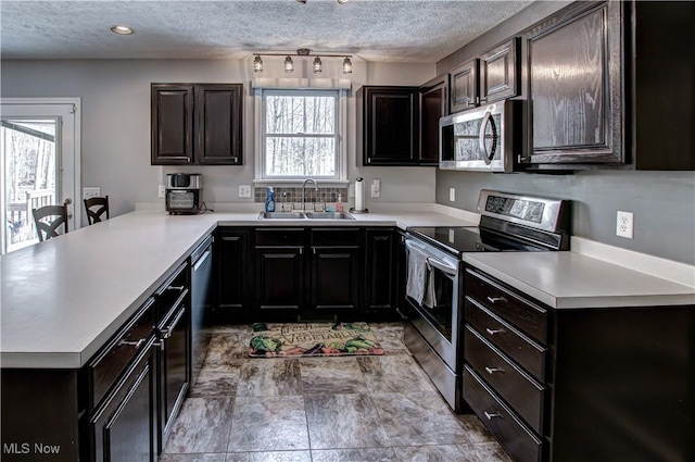 kitchen with kitchen peninsula, appliances with stainless steel finishes, dark brown cabinets, a textured ceiling, and sink