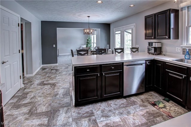 kitchen with pendant lighting, stainless steel dishwasher, a textured ceiling, kitchen peninsula, and a chandelier