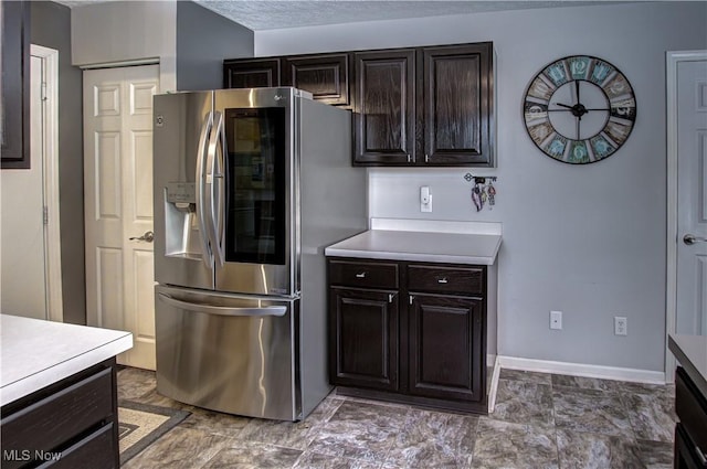 kitchen with stainless steel fridge, a textured ceiling, and dark brown cabinets