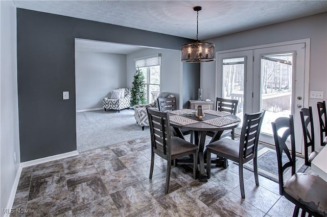 dining space with carpet flooring, plenty of natural light, a textured ceiling, and a notable chandelier