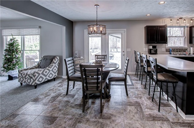 carpeted dining room with a notable chandelier, a healthy amount of sunlight, and sink