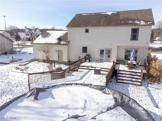 snow covered rear of property with a wooden deck