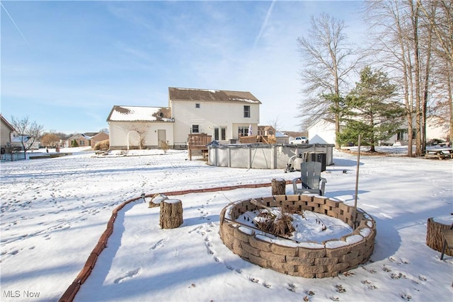 snow covered back of property featuring a fire pit