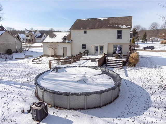 snow covered property with a deck and french doors