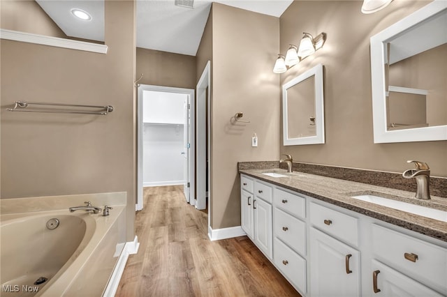 bathroom with a bath, wood-type flooring, and vanity