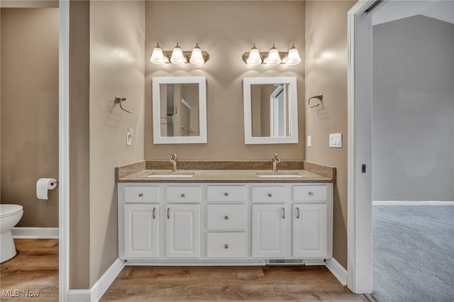 bathroom featuring vanity, wood-type flooring, and toilet