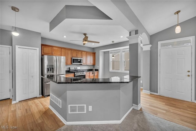 kitchen featuring decorative light fixtures, dark stone countertops, ornate columns, and stainless steel appliances