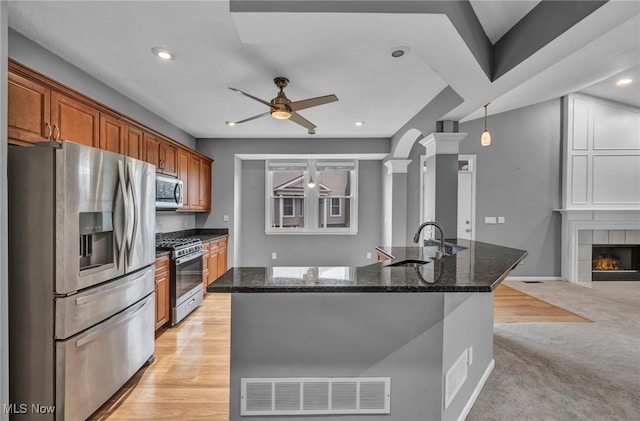 kitchen with ornate columns, sink, dark stone counters, light carpet, and appliances with stainless steel finishes