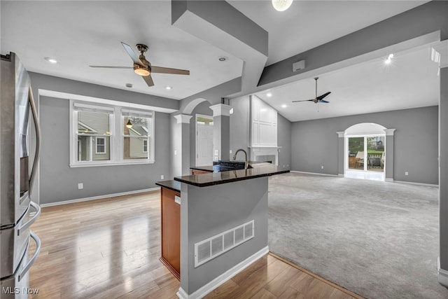 kitchen with lofted ceiling, light carpet, stainless steel fridge, kitchen peninsula, and decorative columns