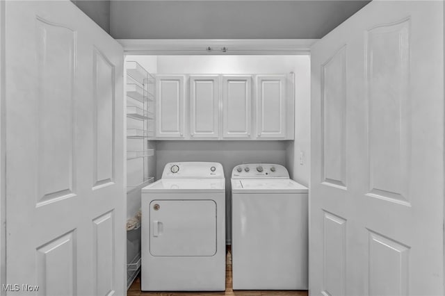 clothes washing area with cabinets, washer and dryer, and wood-type flooring