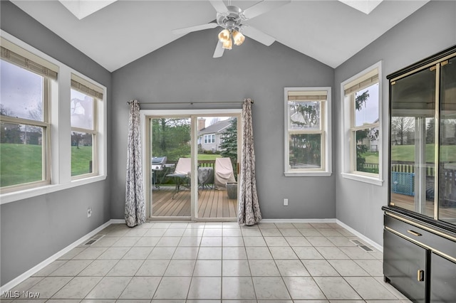 empty room with plenty of natural light, light tile patterned flooring, lofted ceiling with skylight, and ceiling fan