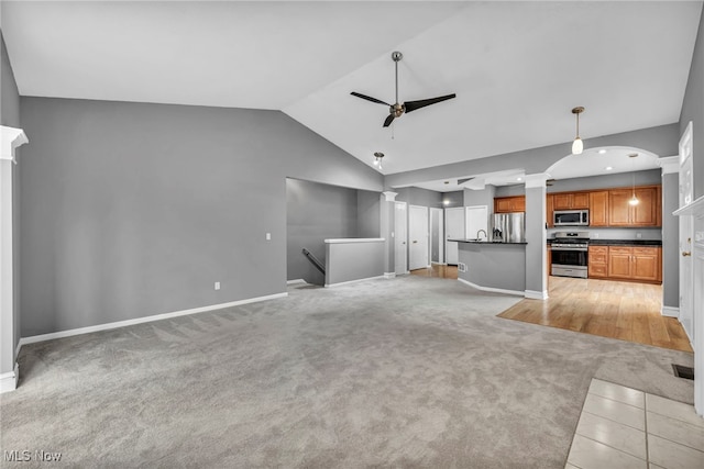 unfurnished living room with light colored carpet, vaulted ceiling, and ceiling fan