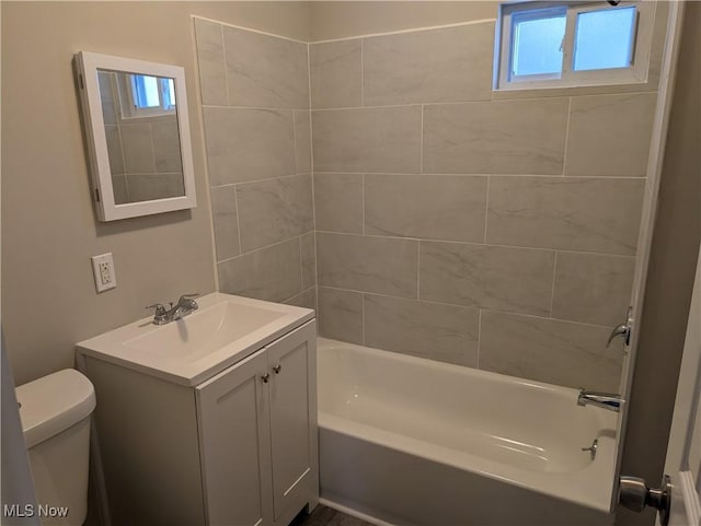 full bathroom featuring vanity, tiled shower / bath combo, and toilet