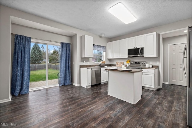 kitchen featuring white cabinetry, a kitchen island, dark wood-type flooring, and appliances with stainless steel finishes