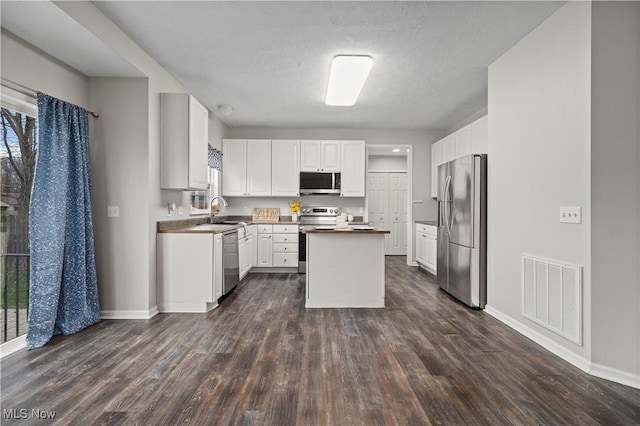 kitchen featuring dark hardwood / wood-style floors, a center island, white cabinetry, and appliances with stainless steel finishes