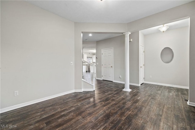 spare room featuring decorative columns and dark hardwood / wood-style flooring