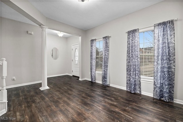 foyer entrance with decorative columns, dark hardwood / wood-style flooring, and a healthy amount of sunlight